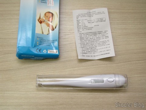 Termômetro Corporal Digital (32~42º C) (Body Temperature Thermometer (32~42′C)) em seu estojo, ao lado de embalagem e manual