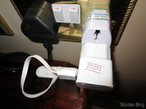 Adaptador Universal para Tomadas do Reino Unido e Irlanda conectando o carregador do Power Bank. O plug do lado esquerdo é o da TV.