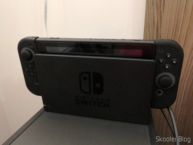 O Nintendo Switch, com a película e as capas, no dock.