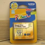Fita p/ Rotulador 12mm x 8m M-231 Brother - Impressão Preta em Fita Branca, em sua embalagem.