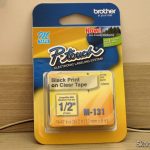 Fita p/ Rotulador M131 12mm Preto sobre Transparente Brother (Ref. M131), em sua embalagem.