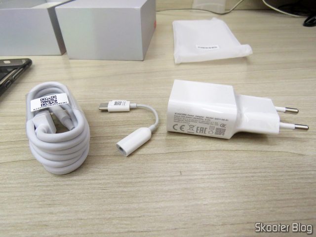 Cabo USB, adaptador para fones de ouvido, e fonte de alimentação.