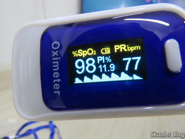 Oxímetro de Dedo OLED em Inglês e Português, em funcionamento.