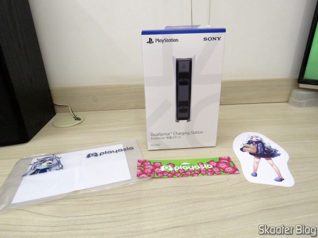 DualSense Charging Station em sua embalagem e brindes da Play-Asia.